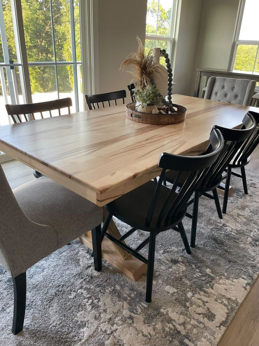 Dining room with a wooden table and black chairs on a patterned rug.